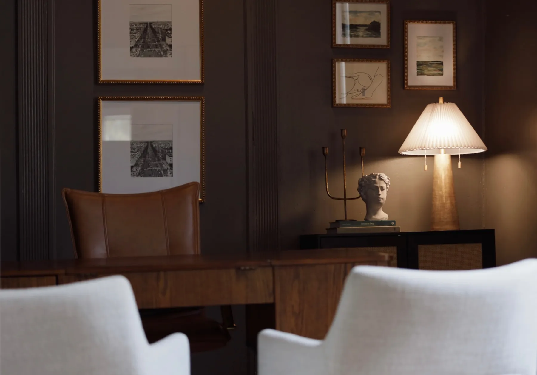 Dark-paneled office meeting room with framed prints and lamplight, designed by Renaissance Design Co.